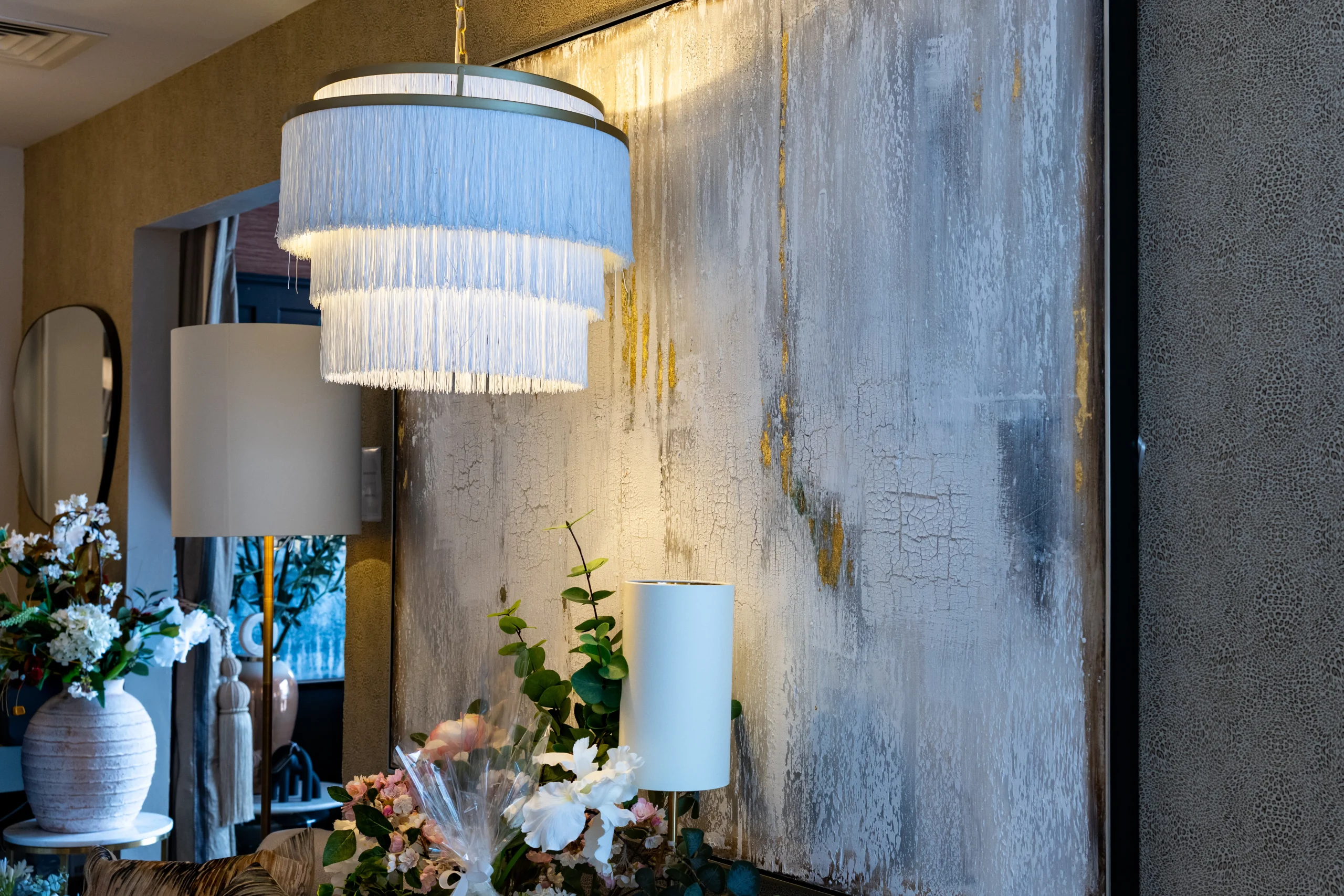 White tiered fringe pendant chandelier beside abstract silver gold canvas wall art