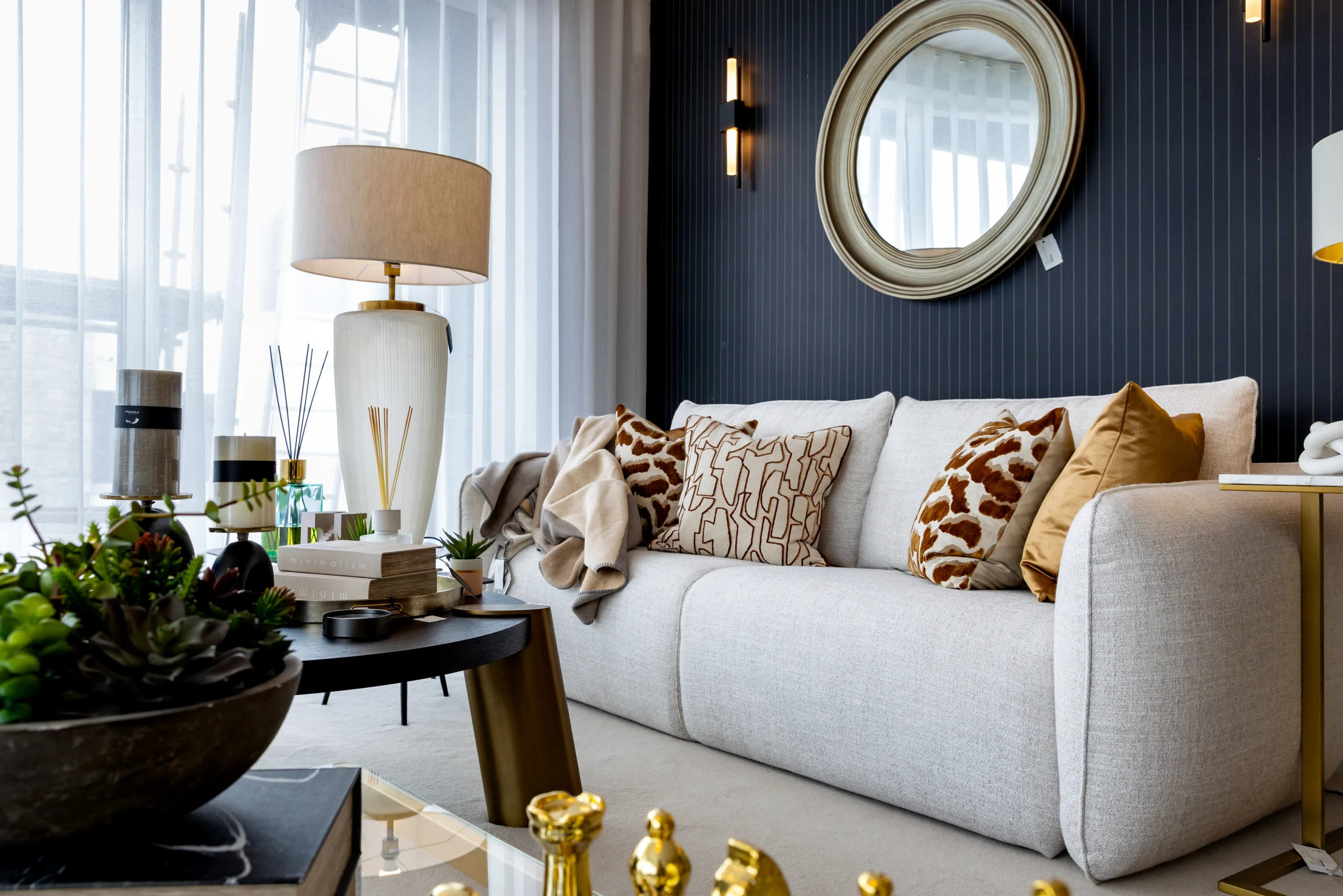 Gavelle living room with grey fabric sofa, ochre velvet cushions, navy wall and gold floor lamp