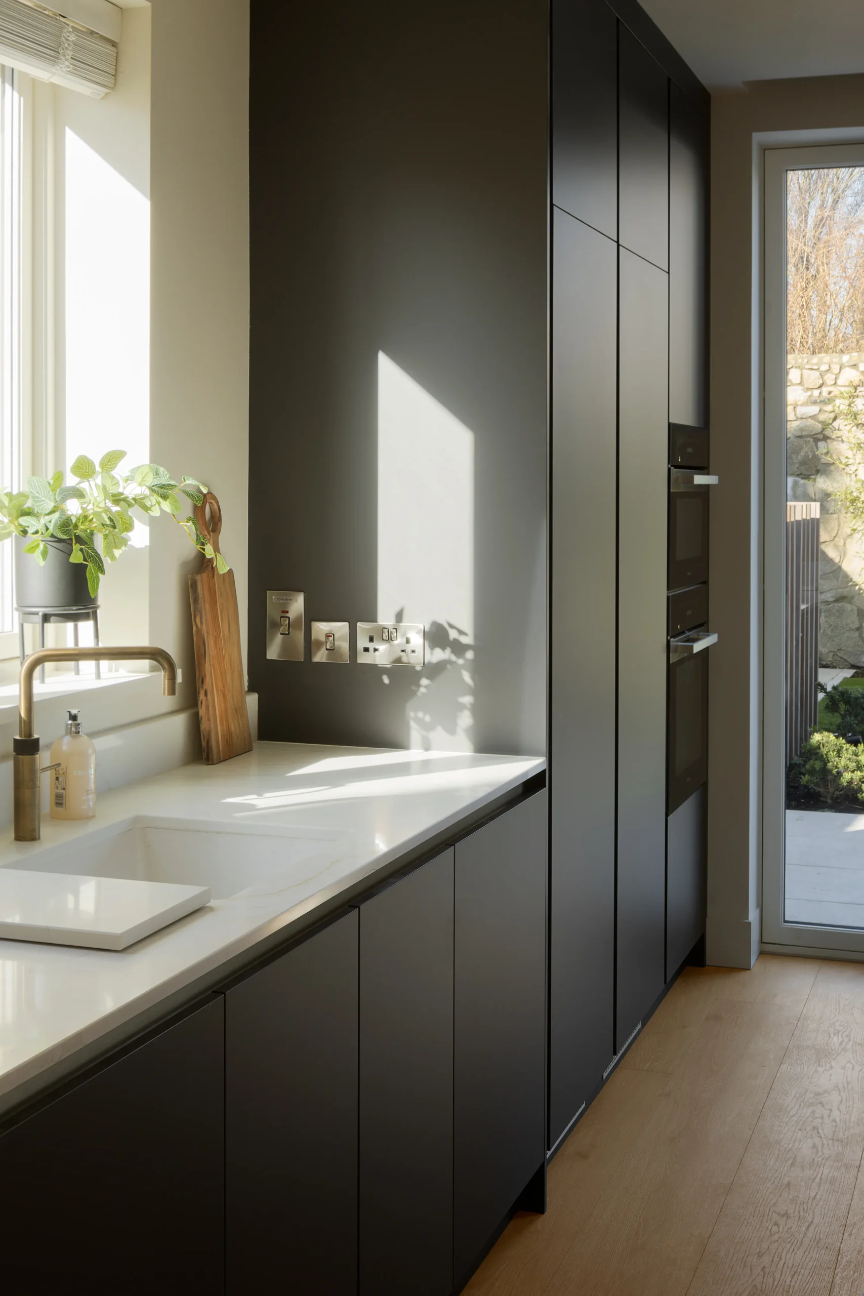 Interior design and joinery detail from the Blackrock home by Gavelle, in a palette of matte charcoal, warm oak, brushed brass and natural stone