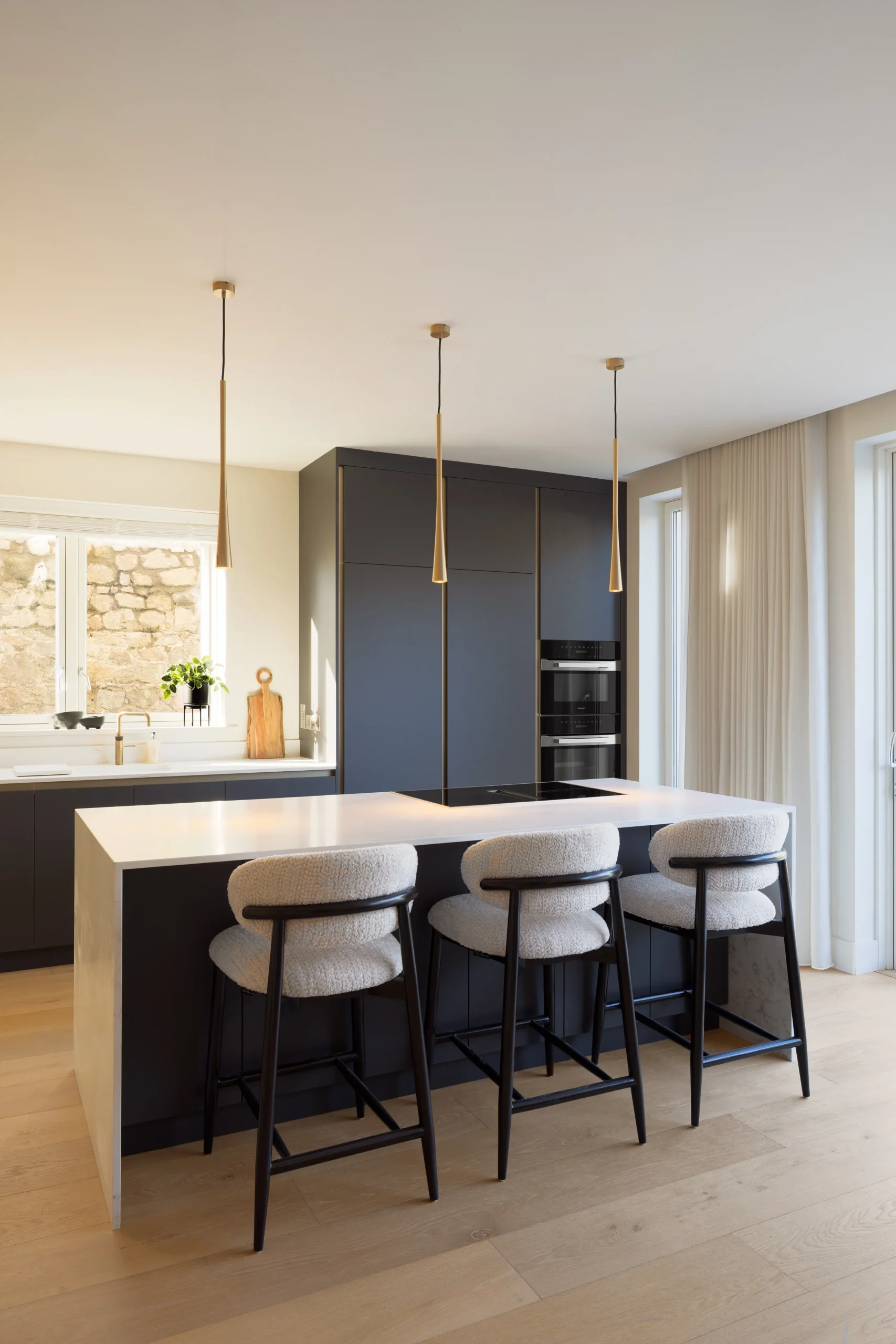 Quartz waterfall island and matte black kitchen with garden doors and soft natural light