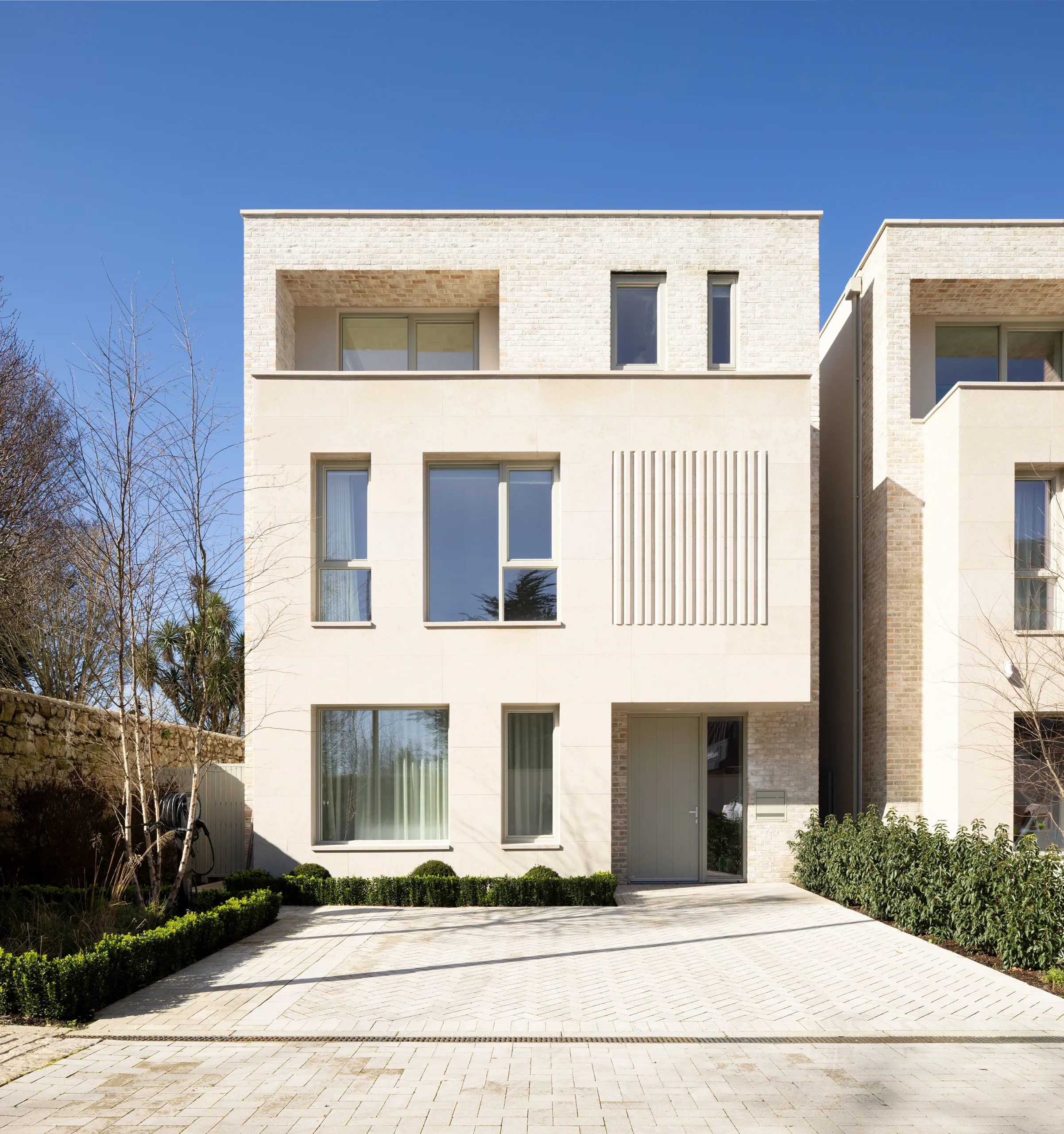 Limestone and brick exterior of the Blackrock home with herringbone stone driveway and clipped box hedging